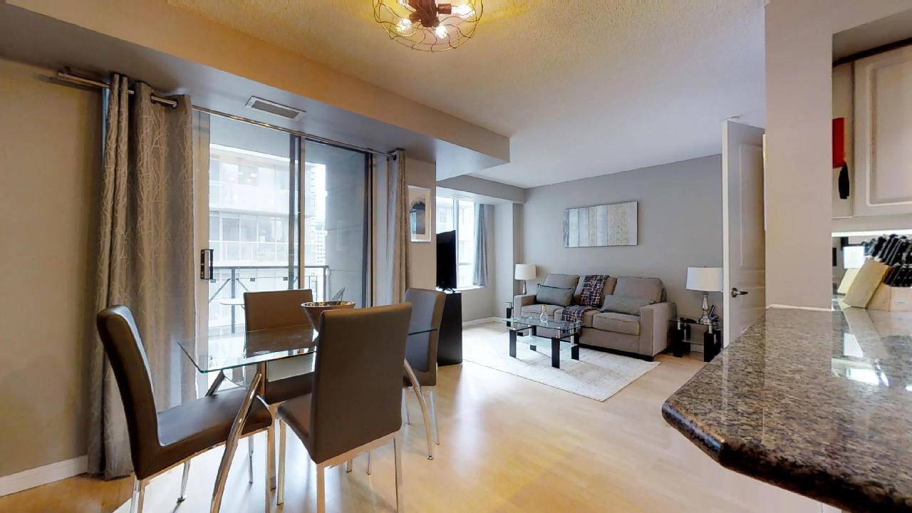 balcony, dining table, and living area with flat screen TV near university and queen in a furnished apartment