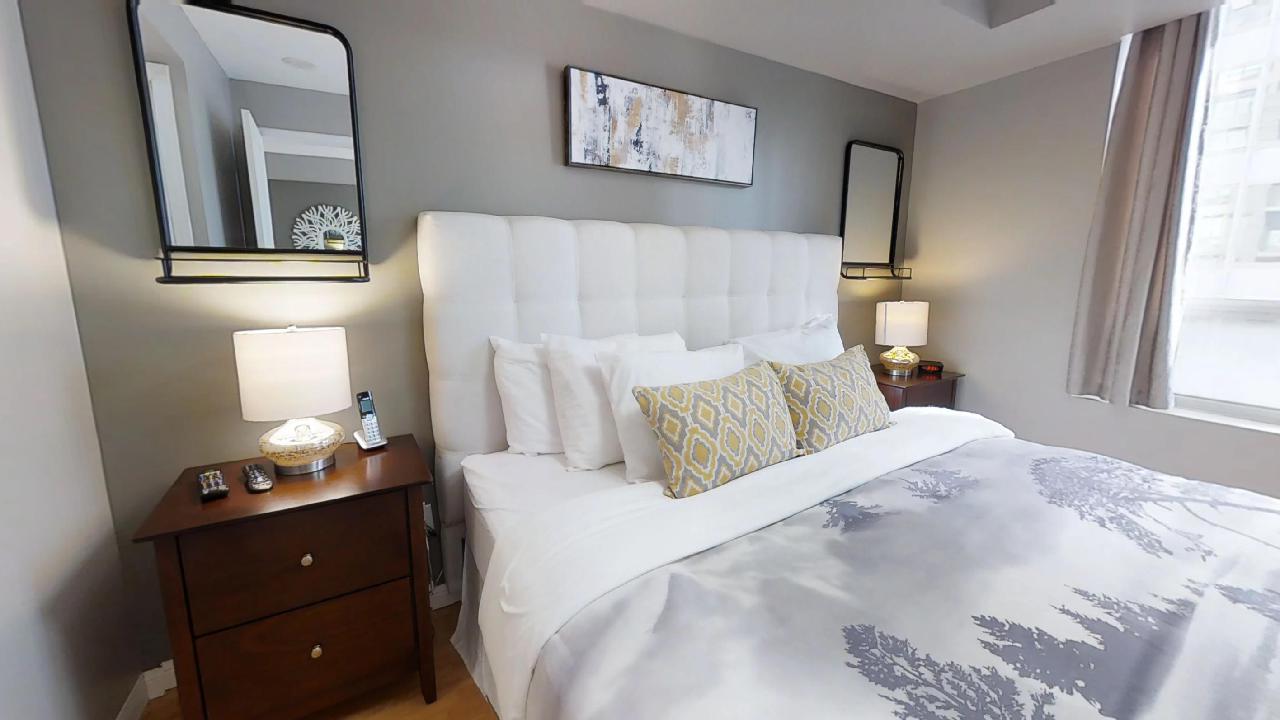 Pillows and blue duvet in the master bedroom in a University Plaza furnished apartment in Toronto