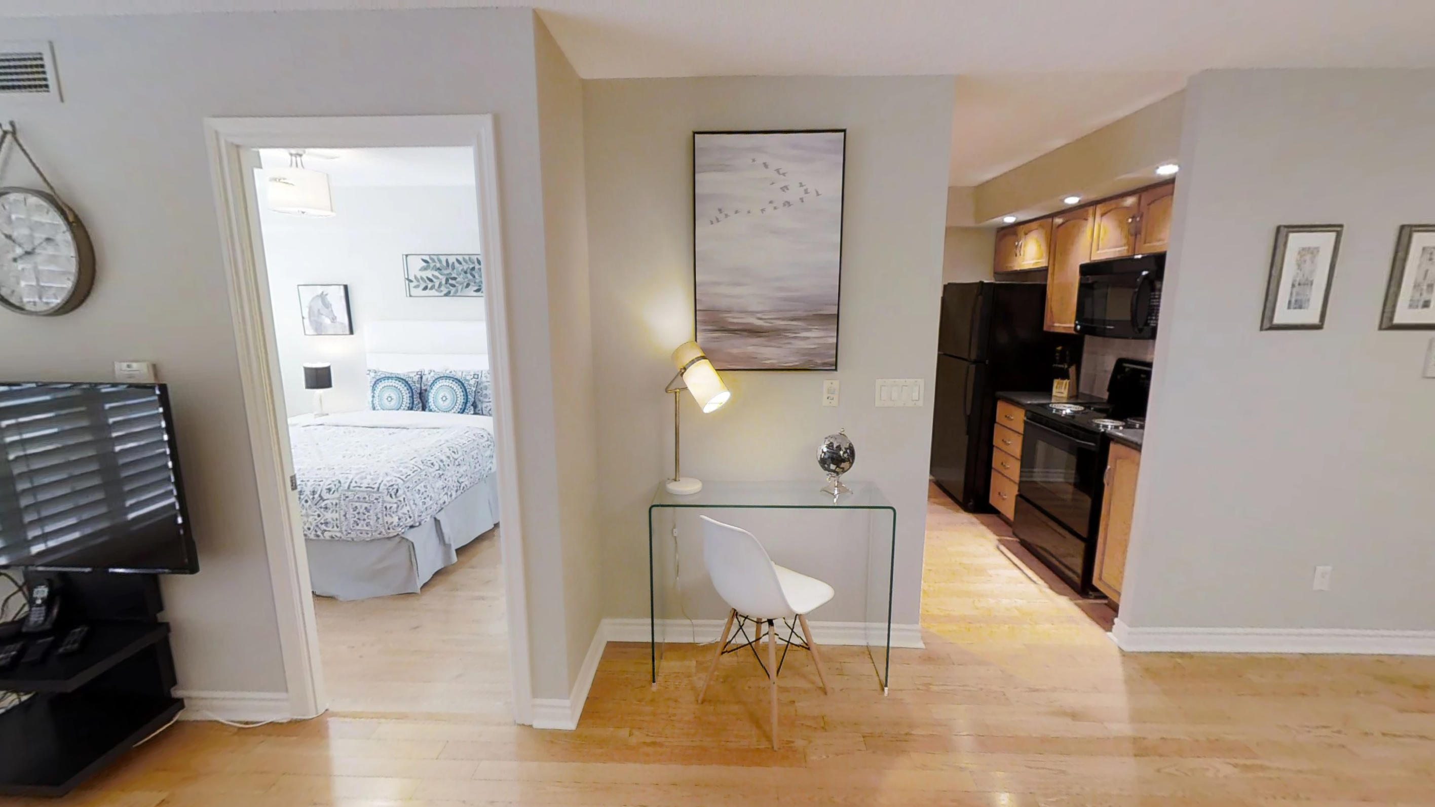 the glass desk and view to the bedroom in a one bedroom toronto furnished apartment near blue jays way and wellington streets