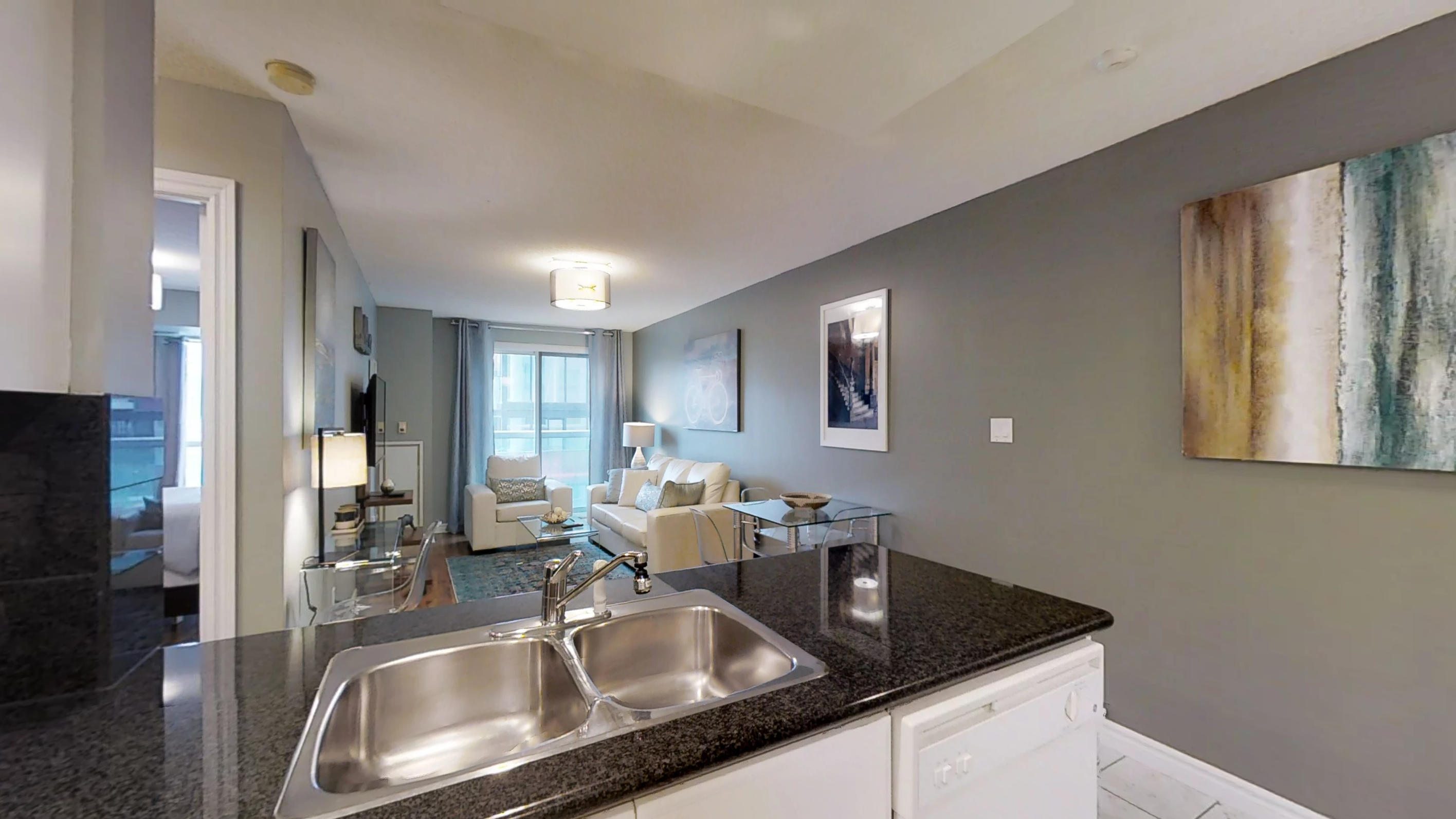 The kitchen sink and living room of a toronto extended stay suite, near osgoode station